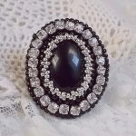 Bague Stone Noire avec un cabochon en Onyx orné de chatons en Cristal à laquelle s’ajoute des rocailles Argentées qui complètent le Noir sur bague Nickel en Laiton et une feutrine. Un style Rétro